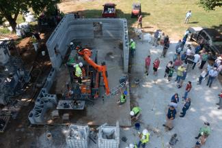 A bird’s-eye view shows the crowd that gathered in Somerset to watch Kentucky’s first 3D-printed home take shape. The completed back wall and curved design show how the structure’s geometry helps it stand up to tornadoes and flooding